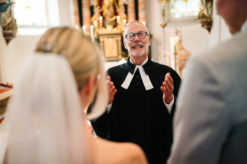 Pfarrer lacht mit der Braut während der Trauung