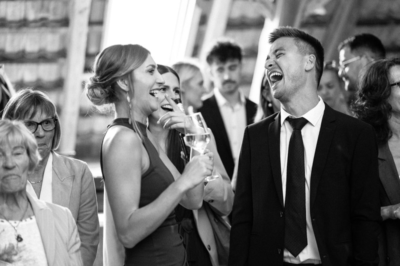Gäste lachen beim Empfang im Stadel, Schwarzweiß