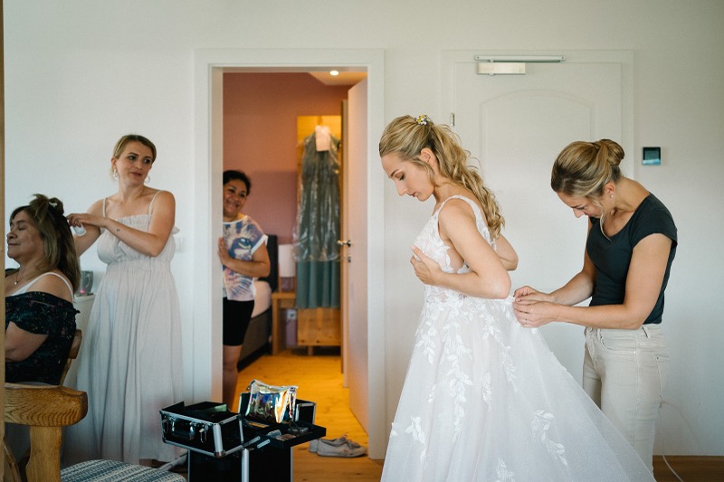 Braut wird ins Kleid geholfen